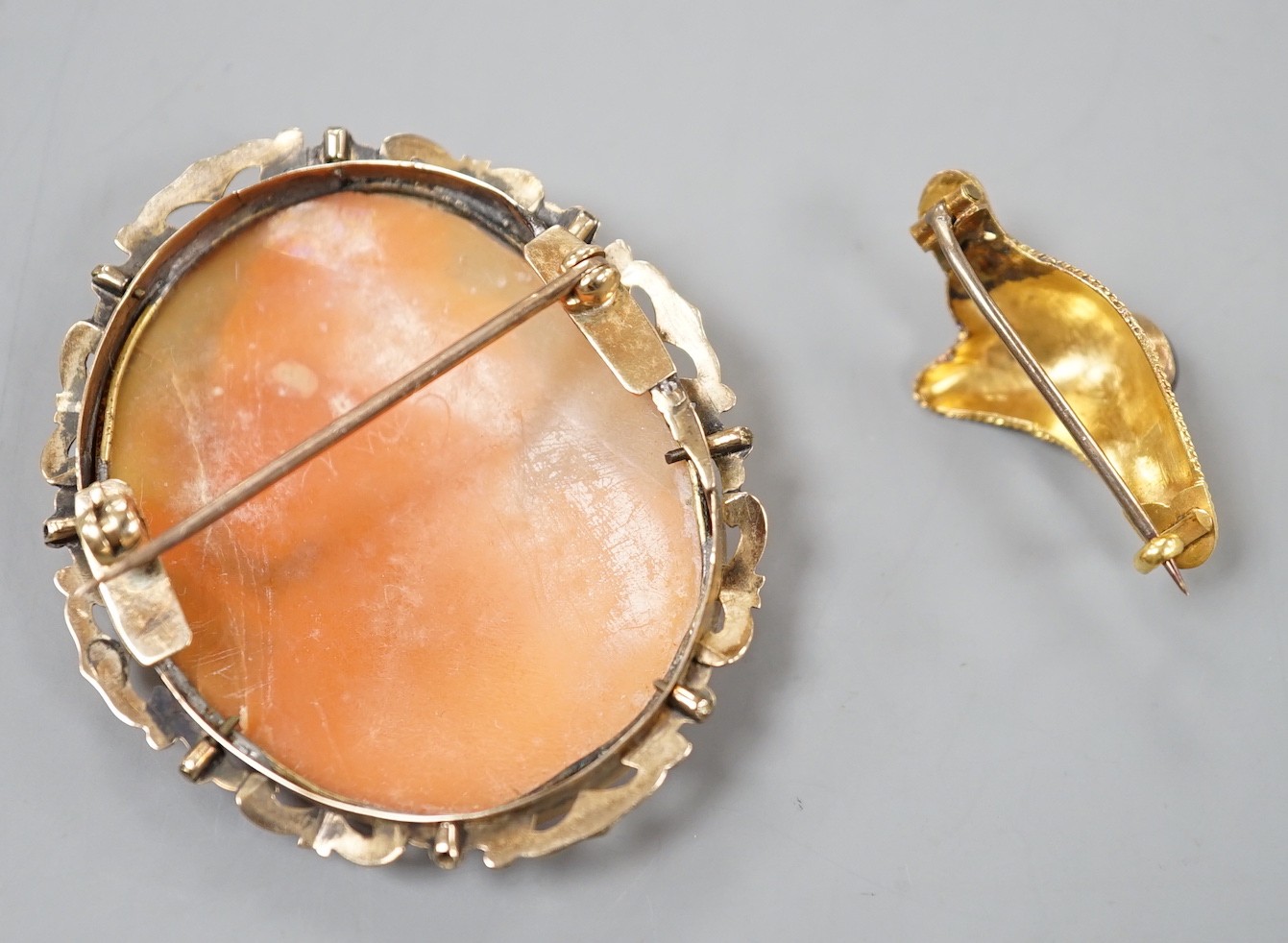A yellow metal, garnet and seed pearl set brooch, 30mm gross 1.7 grams and a yellow metal mounted oval cameo shell brooch, 49mm, gross weight 10 grams.